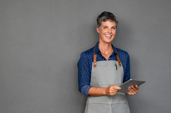 Mature woman in apron holding digital tablet — Stock Photo, Image