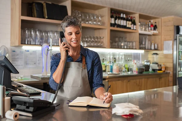 Trabalhador da loja de café tomando ordem sobre o telefone — Fotografia de Stock