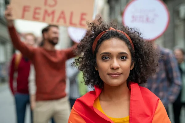 Multiethnic girl at woman empowerment strike on street. Portrait of mixed race girl in rally to protest on equality for woman looking at camera. Multiracial woman in march fighting for woman freedom and lgbt rights.