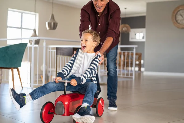 Senior Man Hjälper Pojken Rida Sin Leksaksbil Hemma Farfar Knuffade — Stockfoto