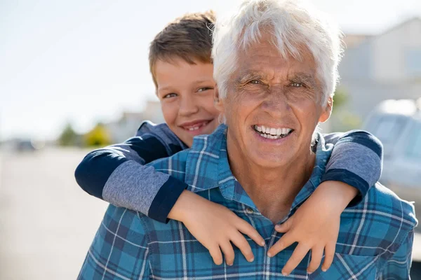 Großvater Trägt Enkel Huckepack Durch Die Nachbarschaft Glücklicher Älterer Mann — Stockfoto