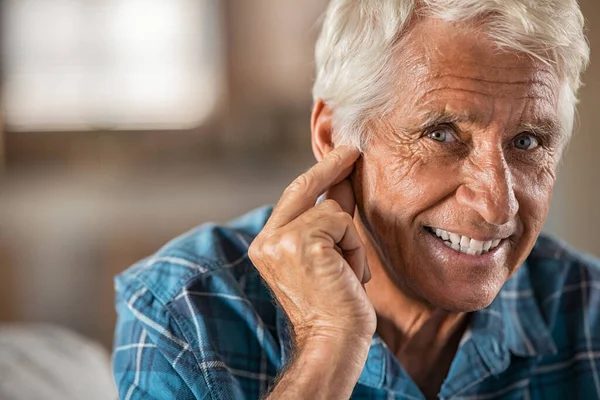 快乐的男人在家里带着助听器终于听到了 复制空间 面带微笑的老年人满意地举着耳朵看着相机的画像 老人用他的新助听器在家里放松地紧闭着脸 — 图库照片