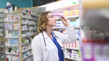 Eczanedeki yetişkin kadın eczacının portresi. Steteskoplu işçi ceketi giyiyor. Gülümseyen mutlu doktor eczaneden ilaç alıyor. Dost canlısı eczacı kameraya bakıyor..