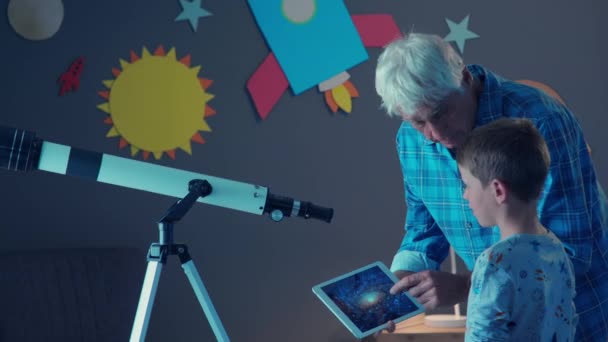 Radosny Dziadek Pokazujący Szczęśliwemu Wnukowi Gwiazdy Galaktyki Tablecie Cyfrowym Uśmiechnięty — Wideo stockowe