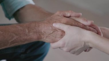 Kızların, babalarının elini tutarken yakın çekim. Yaşlı adamı teselli eden bir kadının ayrıntılı eli. Yardım eden eller, bakım ve yaşlılar konsepti.