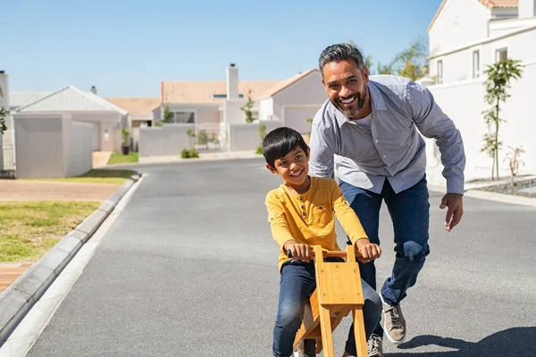 Feliz Pai Latino Ajudando Menino Sorridente Andar Bicicleta Equilíbrio Madeira — Fotografia de Stock
