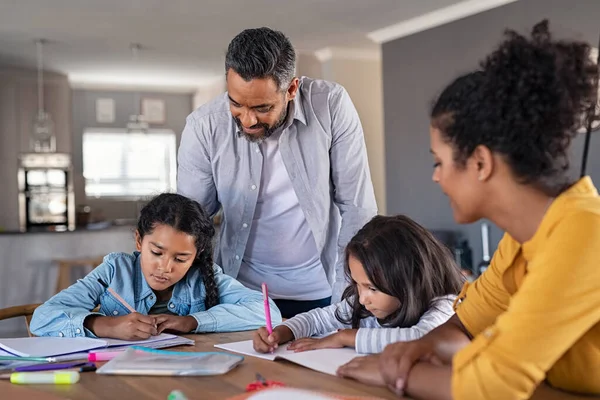 インド人の両親は家で子供の宿題を手伝っている 中東の父とアフリカの母は 家庭で勉強する娘を助けています 小さな女の子はお父さんとお母さんの助けを借りて彼らの演習を完了します ホームスクーリングの概念 — ストック写真