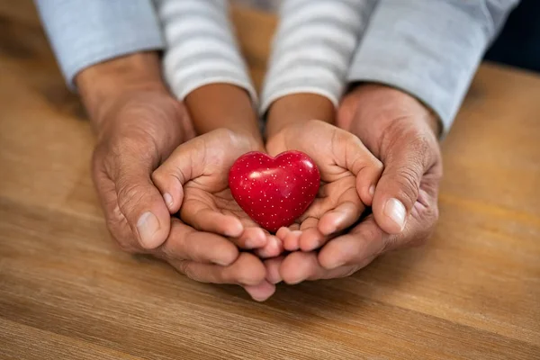 Familia Sosteniendo Pequeño Corazón Rojo Las Manos Sobre Fondo Madera — Foto de Stock