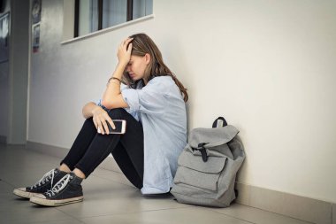 Üzgün ve depresif bir kız elinde akıllı telefonuyla kampüs zemininde kafa tutarak oturuyor. Lisede yerde oturan üzgün bir üniversite öğrencisi depresyondan muzdarip. Kopya boşluğunda zorlanan yalnız bir genç..