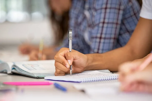 非洲裔学生在课堂上手拉手地在笔记本上记笔记 高中图书馆中青年手握笔准备考试的情况介绍 在课堂上做笔记的大学生 — 图库照片