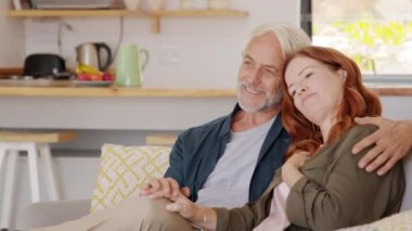 Kanepede otururken kucaklaşan neşeli, olgun bir çift. Yaşlı adam ona sevgiyle bakarken bir kadına sarılıyor. Sevgi dolu yaşlı koca, evde gülümseyen karısından kucaklaşıyor..