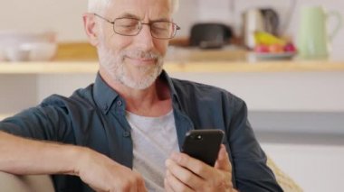 Evde yemek siparişi verirken elinde akıllı telefon tutan bir adam. Olgun bir adam yemek siparişi vermek için akıllı telefonlu mobil uygulama kullanıyor. Cep telefonuyla eve e-posta gönderen adam.