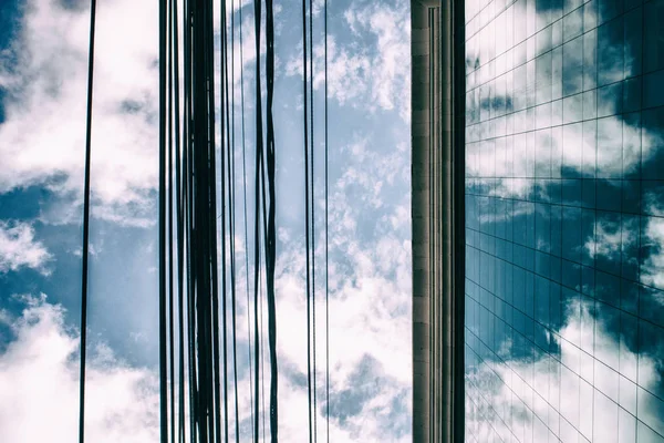 Nubes en un cielo azul reflejadas en ventanas de cristal de un edificio de oficinas — Foto de Stock