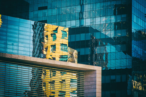 A Mall made of glass windows reflects a yellow building nearby.