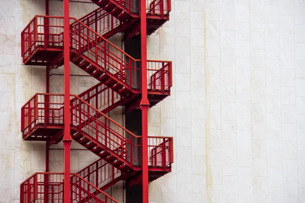 Escadas de emergência externas vermelhas em uma parede branca — Fotografia de Stock