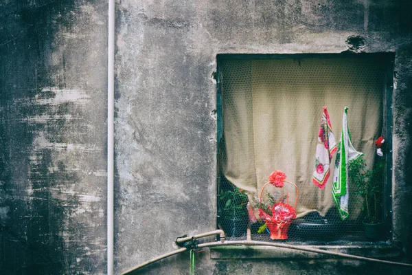 Ventana cuadrada con flores y banderas en un edificio de mala calidad . —  Fotos de Stock