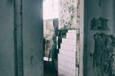 Worn bathroom walls with cracked white tiles.