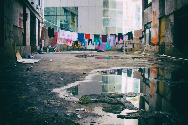 五颜六色的衣服挂在潮湿的腐烂的住宅建筑上晾干. — 图库照片