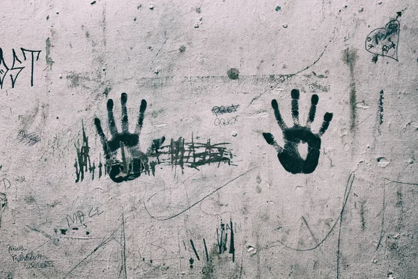 Right and Left hand print marks on a shabby wall.