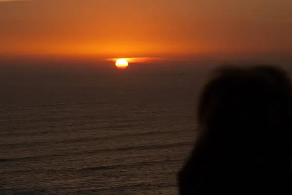 Personensilhouette beim Blick auf den Sonnenuntergang im Meerwasser. — Stockfoto