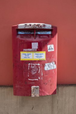 Kırmızı beton ve mermer duvar içinde belgili tanımlık geçmiş ile kırmızı posta kutusu.