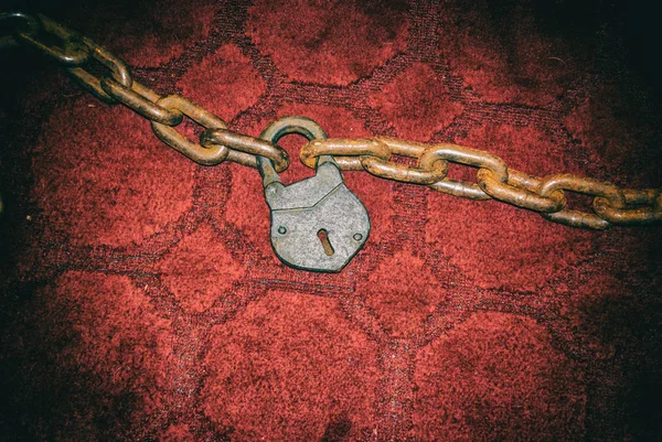 Vintage chaîne rouillée avec cadenas sur tapis rouge  . — Photo