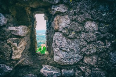 Antika bir taş duvar bir dikdörtgen penceresinden manzara.
