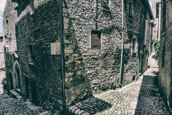 View of an alley with houses of the ancient stone made medieval town of Sermoneta, Italy. History wallpaper background. No people.