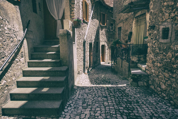 View of an alley with houses of the ancient stone made medieval town of Sermoneta, Italy. History wallpaper background. No people.