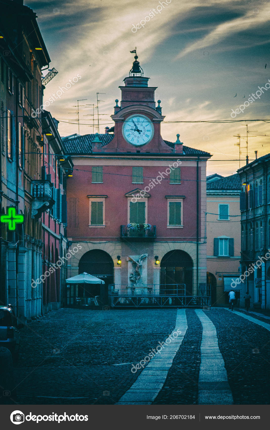 Clock tower and pharmacy sign of a street in an old town in Italy