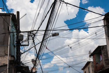 Elektrik ve tv teller mavi gökyüzü ve bulutlar arka plan ile mahallede.