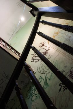 Duvarlara dikey görünüm graffiti ile terk edilmiş bir vintage evde kömür ahşap merdiven. Hiçbir insan.