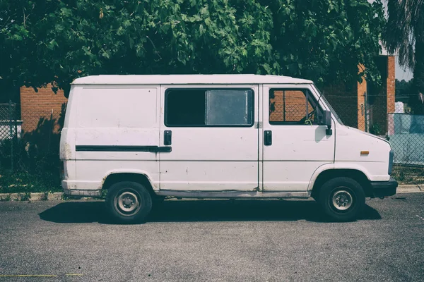 Eski beyaz teslimat kamyonu kurye van ağaçları içinde belgili tanımlık geçmiş ile bir tuğla duvar önünde park etmiş. Hiçbir insan.