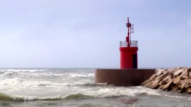 Deniz suyu geçerli ve liman erişim kırmızı fener kulesi ile dalgalar bir dalga Emanet bariyer kayalardan görüntülendi?.