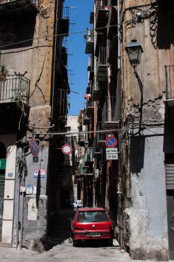 Dikey görüntü eski yıpranmış binalar ve yolda Palermo, İtalya, güzel bir yaz günü mavi gökyüzü arka plan ile tıkayan Park kırmızı bir araba ile bir ara sokakta. Hiçbir insan.