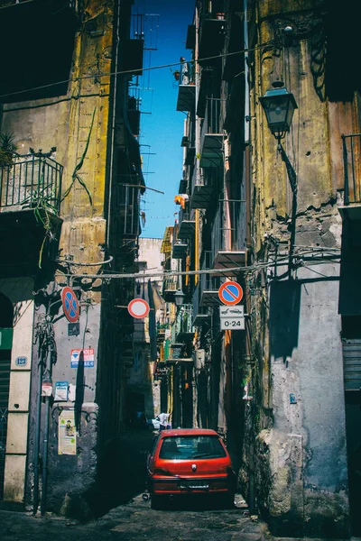 Dikey görüntü eski yıpranmış binalar ve yolda Palermo, İtalya, güzel bir yaz günü mavi gökyüzü arka plan ile tıkayan Park kırmızı bir araba ile bir ara sokakta. Hiçbir insan.