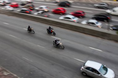 Pan çekim yönünü lane karşısında daha yavaş araba ile yakındaki bir binadan şehir merkezinde bir cadde üzerinde yüksek hızda motosiklet. Hiçbir insan.