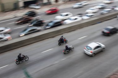 Pan çekim yönünü lane karşısında daha yavaş araba ile yakındaki bir binadan şehir merkezinde bir cadde üzerinde yüksek hızda motosiklet. Hiçbir insan.