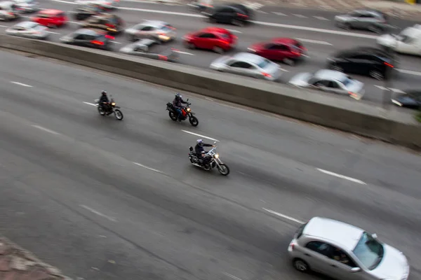 Pan çekim yönünü lane karşısında daha yavaş araba ile yakındaki bir binadan şehir merkezinde bir cadde üzerinde yüksek hızda motosiklet. Hiçbir insan.