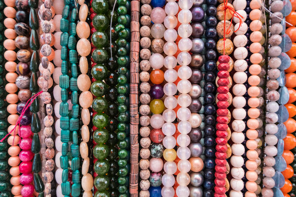 Wallpaper background of colorful necklace made of gemstones and colored beads showcased in a shop. Semi precious jewelery.