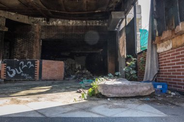 Kırmızı tuğla duvarlı bir eski püskü harap yatak ile çöp dolu eski bir kulübün giyilen iç üzerine bitki ile katta terk edilmiş. Çürük penceresinden girdikten güneş ışık.