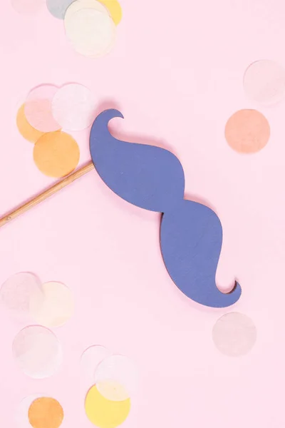 Pastel pembe arka plan üzerinde renkli konfeti bir sürü mavi sahte bıyık. Tatil konsepti. Düz yatıyordu.