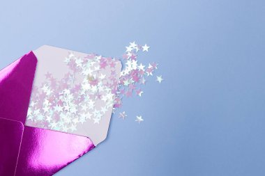 Mavi bir arka plan üzerinde bir form yıldız glitter konfeti ile parlak pembe zarf. Şenlikli konsept.