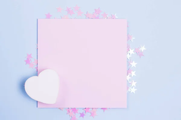 Pastel pembe boş kart mockup ve dağınık pembe glitter yıldız ile pastel mavi arka plan üzerinde beyaz ahşap kalp. Metniniz için yerleştirin. Gbar tarzı.