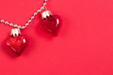 Kırmızı arka plan üzerinde yansıtır ile güzel dekoratif kırmızı cam kalpleri bir çift. Sevgililer Günü Konsepti. Metniniz için yer.