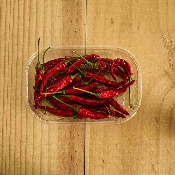 Red hot chilli pepper in a transparent box on wooden background.