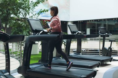 Çekici genç spor kadın spor salonunda çalışıyor. Koşu bandı üzerinde kardiyo egzersizi yapıyor. Modern yeşil spor kulübü koşu bandı üzerinde çalışan.