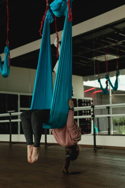 Kadın hamakta hava yoga uygulamaları. Anti-yerçekimi spor specia ekipman ile rahatlatıcı tür. Jimnastik yapmak uzanır ve fiziksel egzersizler sinek-yoga, pilates, gerçekleştirir Onarıcı
