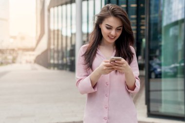 Online haritalar bir alışveriş merkezi için yol bulmak için cep telefonu kullanan güzel esmer kız. Smartphone tarama ve online alışveriş yaparken mutlu kadın. Kadın kişi manifatura cep telefonu.