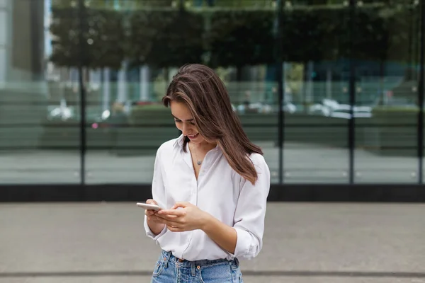 Ofisinin, telefon tarama ve online bir mobil uygulaması alışveriş merkezi yürüyüş gülümseyen süre alışveriş yaparken güzel kadın cep telefonu kullanan mutlu oldukça esmer kız. Online iletişim.